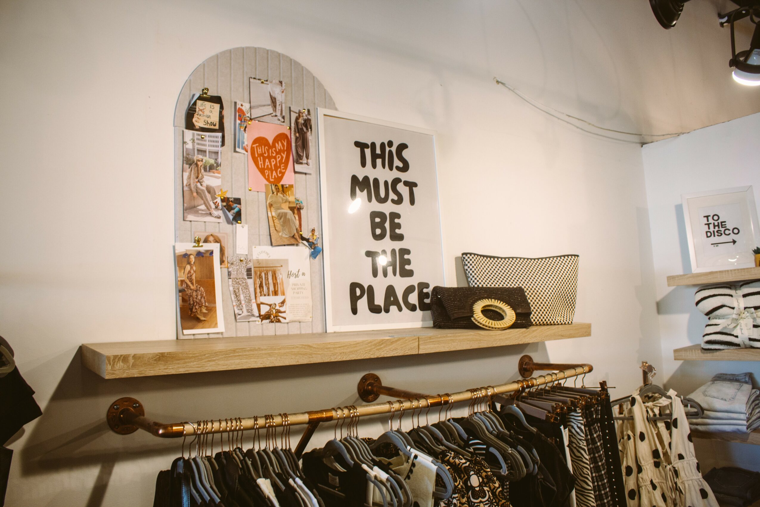 Decorative wall with framed photos, a sign reading 'This must be the place,' and a shelf with a basket and other items.