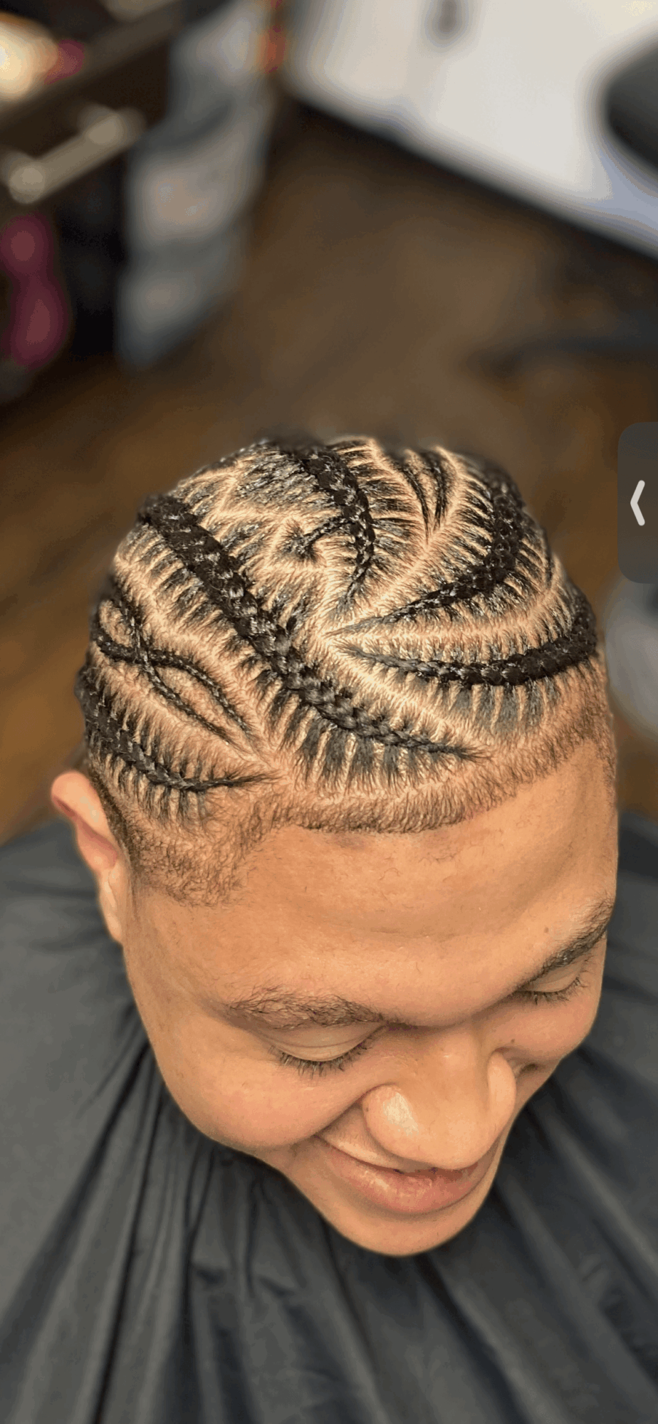 Top view of a person's head with intricate braided hairstyle, showing detailed patterns and cornrows.