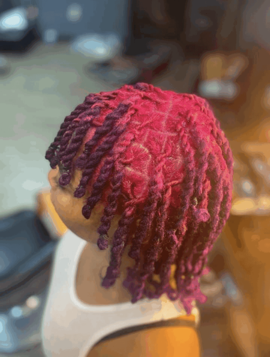 Side view of a person with pink and purple dreadlocks, wearing a white tank top.