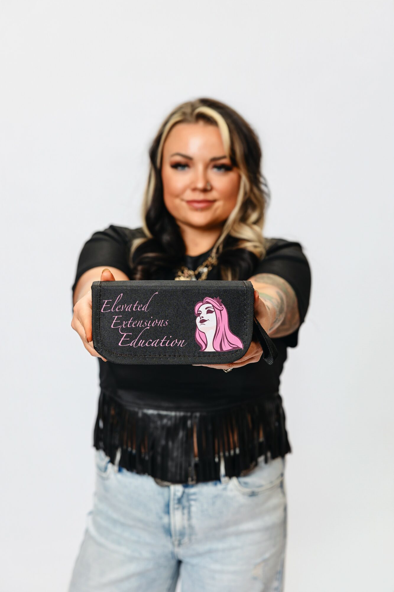 Woman with blonde hair holding a sign with a pink unicorn and text, smiling, against a plain white background.