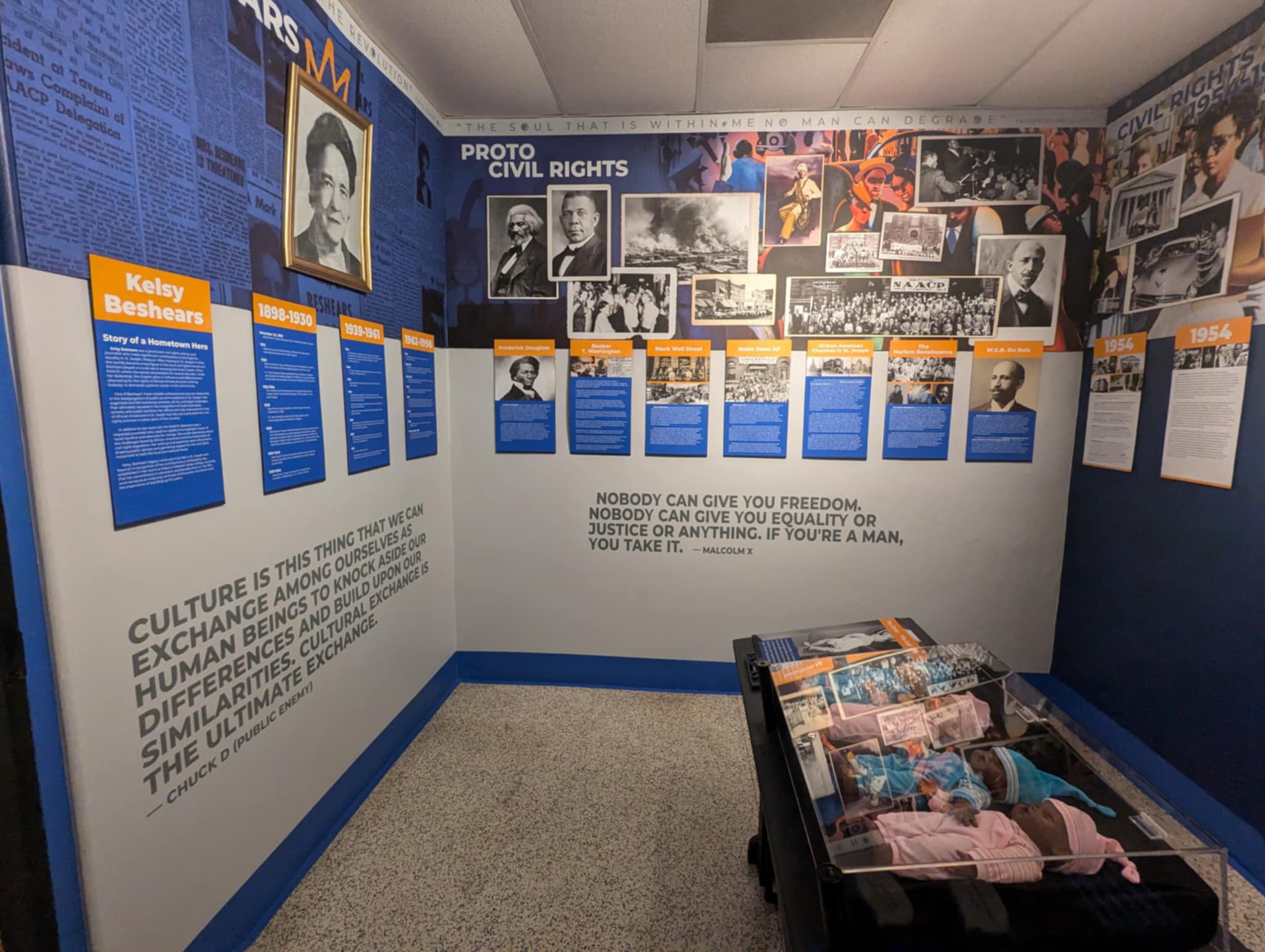 Museum exhibit with photos, text panels, and a display table of folded clothing, focusing on civil rights history.