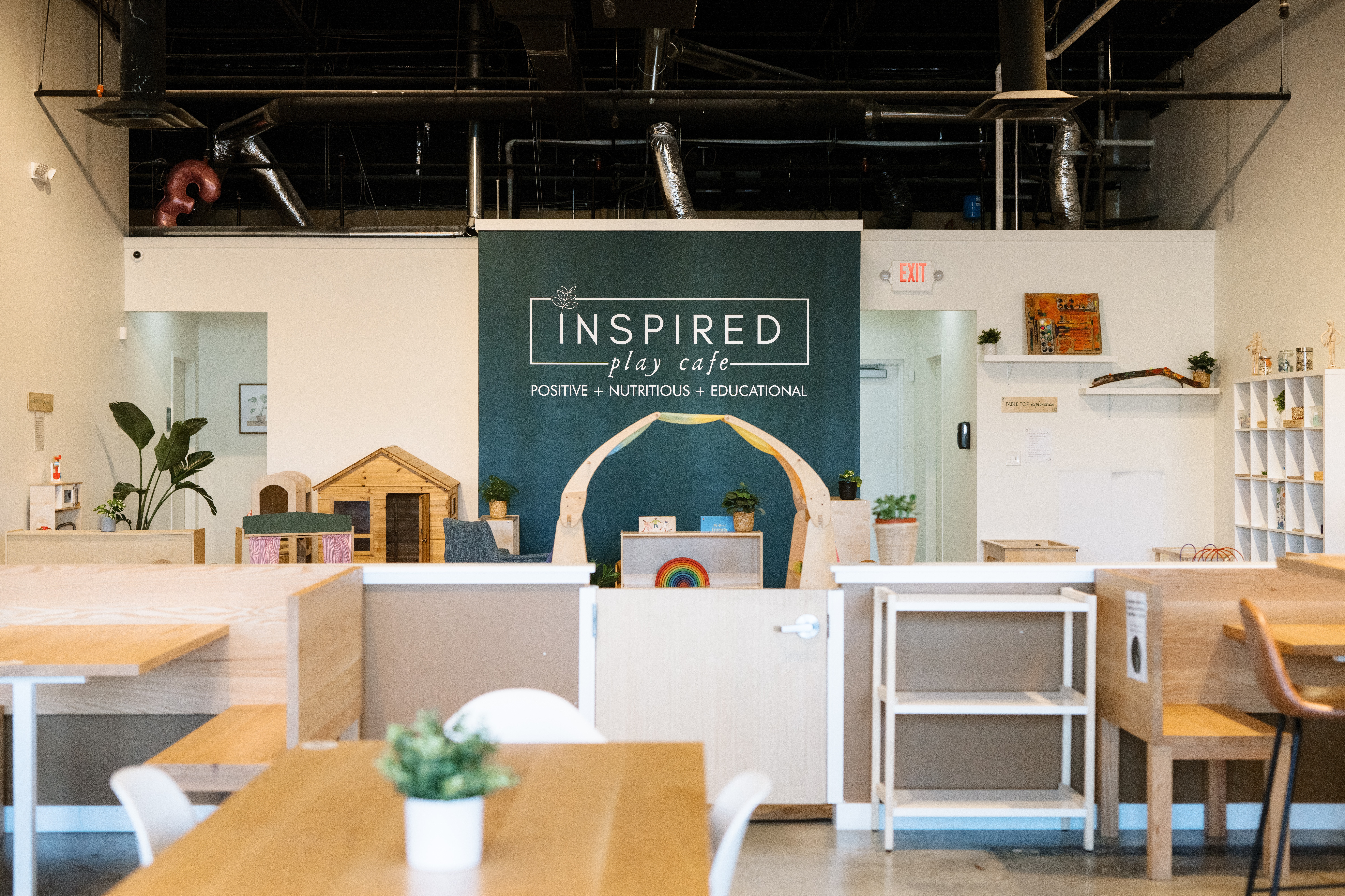 Interior of a classroom or workshop space with a sign reading 'INSPIRED' and various furniture and decorations.