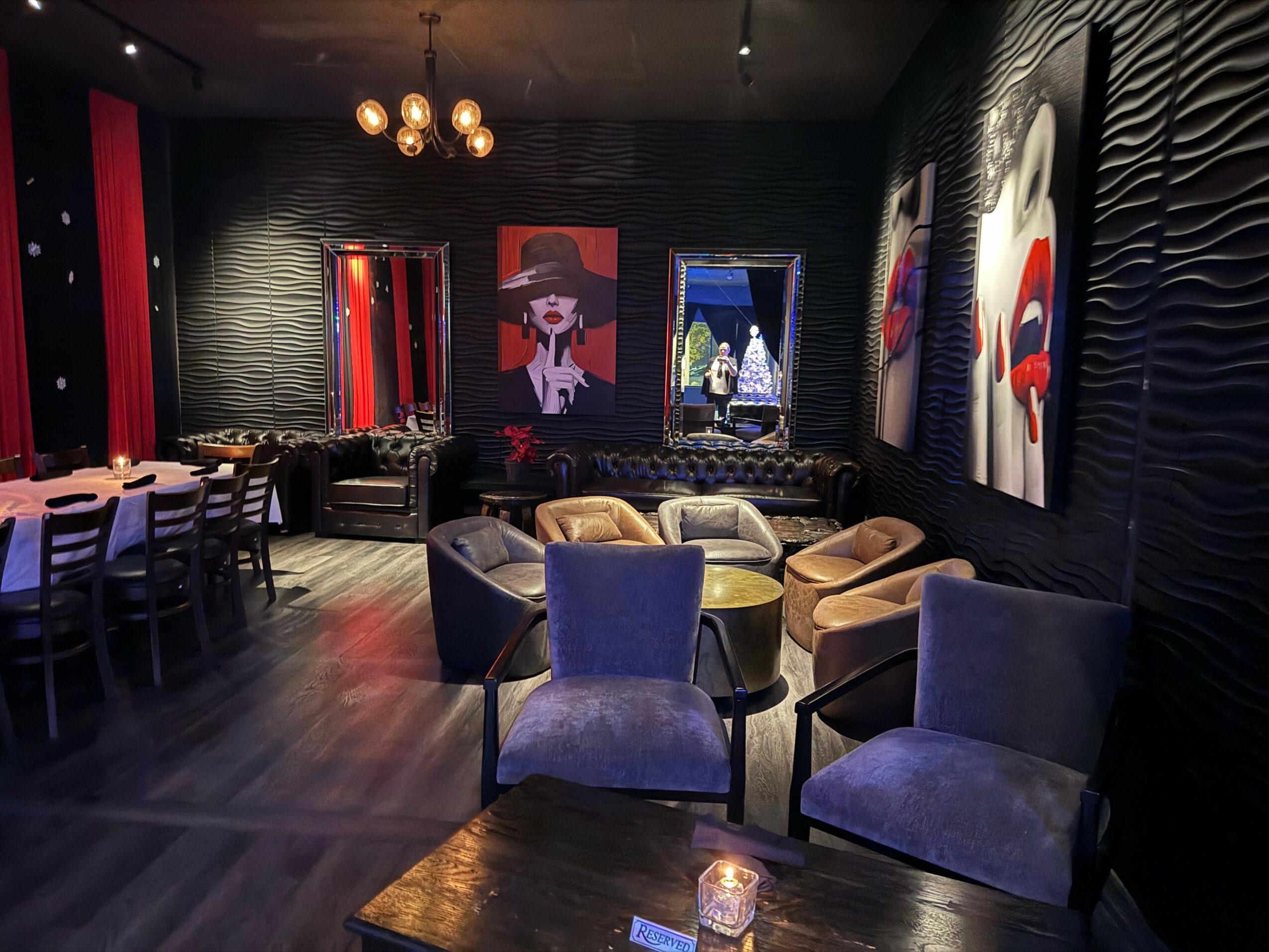 Luxurious lounge with colorful artwork, plush chairs, and dim lighting, creating an elegant atmosphere.