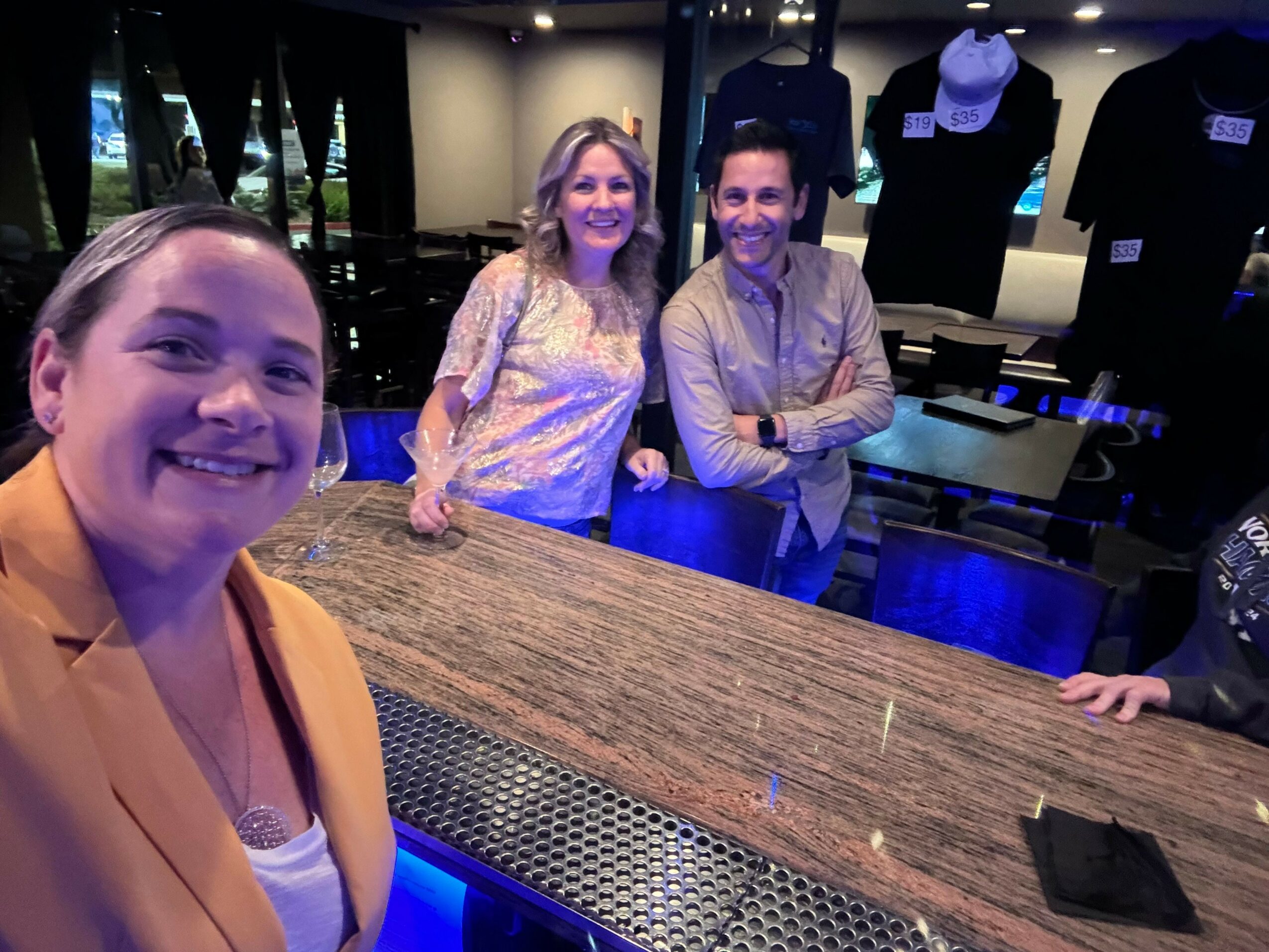 Four people sitting at a table in a dimly lit room, smiling and looking at the camera.